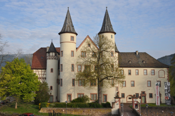Frontalansicht des Lohrer Schlosses, in dem das Spessartmuseum untergebracht ist. Vor dem Schloss steht eine große Linde, die gerade erst grün wird.